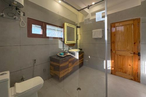 a bathroom with a toilet and a glass shower at The Verra Homestay in Kulu