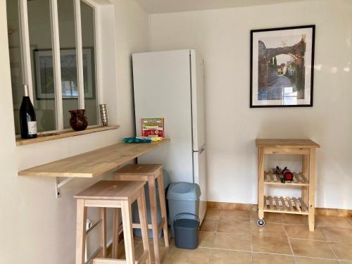 een keuken met een koelkast, een tafel en een kruk bij Charmante maison avec jardin et air conditionné au coeur d'un village historique ! in Verneuil-en-Bourbonnais