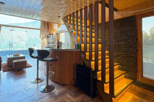 a room with a staircase and a bar with chairs at The Verra Homestay in Kulu