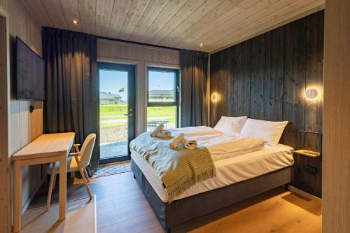 a bedroom with a bed and a desk and a window at Arctic Apartments - Ramberg Beach in Ramberg