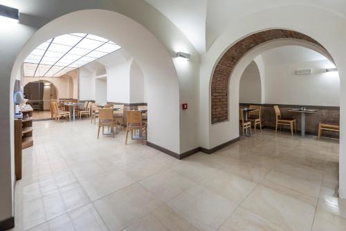 Un comedor con arco y mesas y sillas. en Hotel California, en Roma