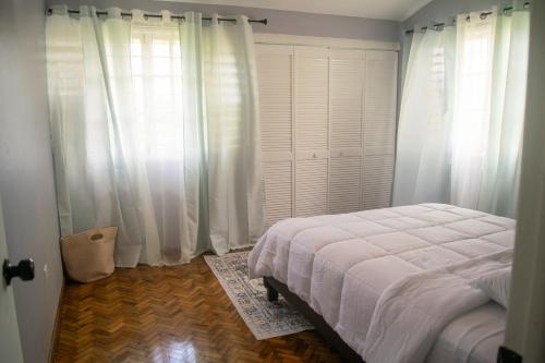 a bedroom with a white bed and white curtains at 2,3 or 4 Bd townhouse overlooking Kingston in Kingston