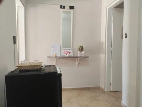 a room with a television and a mirror on a wall at Chalés Caraguá Massaguaçu in Caraguatatuba