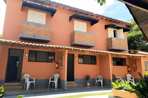 a building with chairs in front of it at Chalés Caraguá Massaguaçu in Caraguatatuba