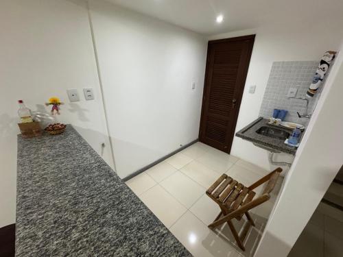 a small kitchen with a counter and a wooden chair at Village Pedra do Sal Lounge Apts in Salvador