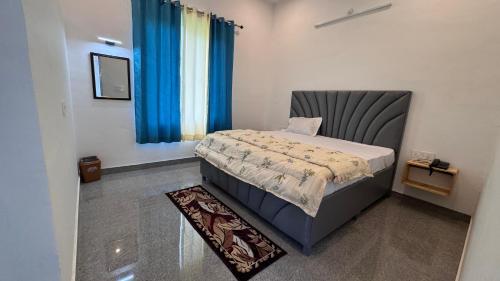 a small bedroom with a bed with blue curtains at J Terminal Hotel & Cafe in Barkot