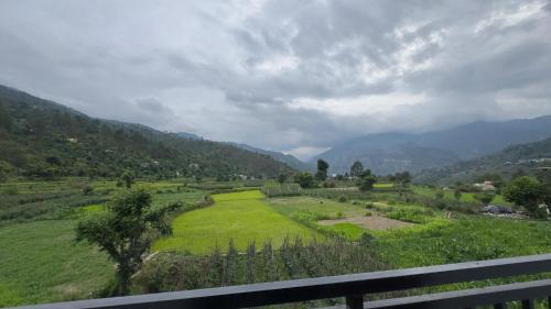 a field of green grass with mountains in the background at J Terminal Hotel & Cafe in Barkot