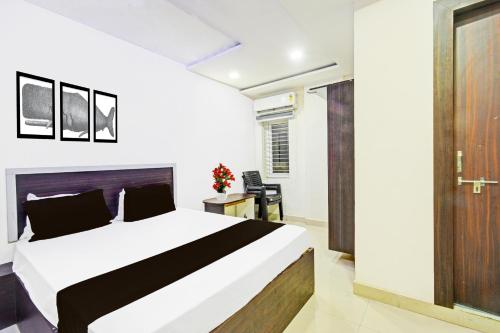 a bedroom with a white bed and a wooden door at Hotel O Mayur Inn in Surūrnagar