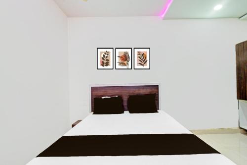 a white room with a bed and three pictures on the wall at Hotel O Mayur Inn in Surūrnagar