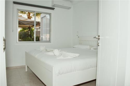 a white bedroom with a white bed and a window at Happy Space Apartment in Los Cristianos