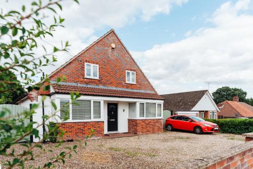 a red car parked in front of a brick house at Lyndale House - North Norwich suburbs in Norwich