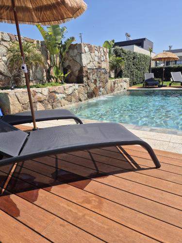 a chair with an umbrella next to a swimming pool at Vivenda pé n'areia in Póvoa de Varzim
