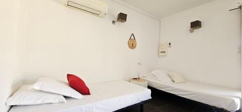 deux lits dans une chambre avec des murs blancs et des oreillers rouges dans l'établissement T2 Résidence Dolce & Vita B3 avec piscine, à Propriano
