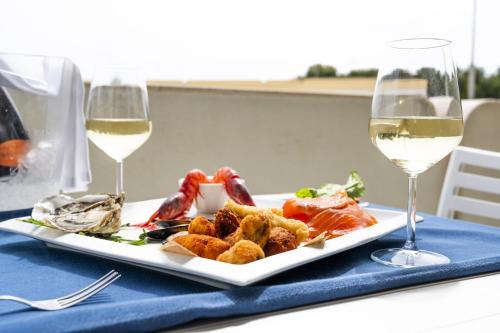 a plate of food on a table with two glasses of wine at Easylife - a 2 passi dal mare Sant'Isidoro in Sant'Isidoro