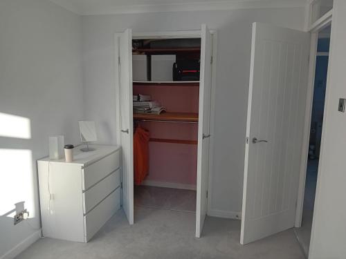 a room with an open closet with a desk and a dresser at 'Ks' Yard in Great Dunmow
