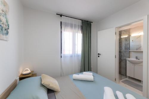 a white bedroom with a bed and a sink at Villa Bijaći in Kastel Novi