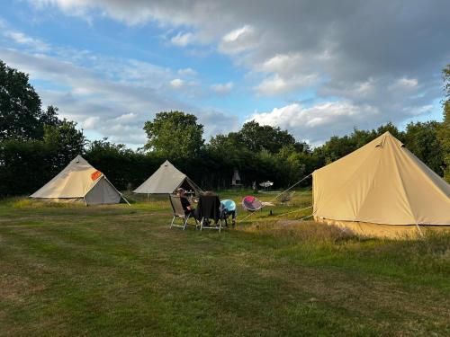 a group of tents in a field with a table and chairs at Bell Tent in Elim