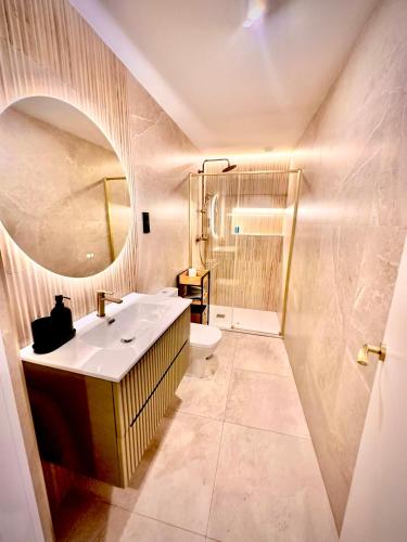 a bathroom with a sink and a toilet and a mirror at SUITE PLAYA CARIHUELA Apartamentos in Torremolinos