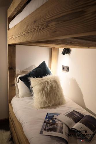 - un lit avec un oreiller et un journal dans l'établissement Résidence Grandes Bosses - Beau penthouse au charme montagnard MAE-5844, à Courchevel