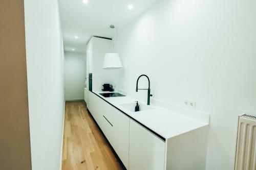 a white kitchen with a sink and a mirror at Dreamy Glyfada Apartment in Athens