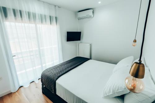 a white bedroom with a bed and a window at Dreamy Glyfada Apartment in Athens