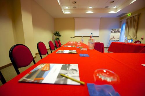 a conference room with a long table with red tables and chairs at Mercure Genova San Biagio in Genova