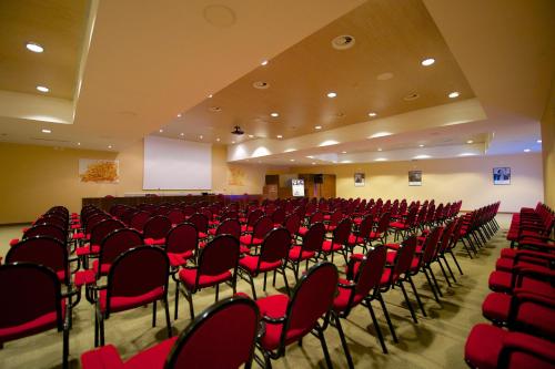an empty room with red chairs and a podium at Mercure Genova San Biagio in Genova