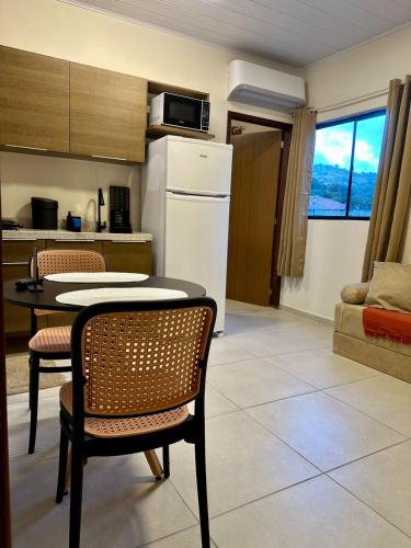 a kitchen with a table and chairs and a refrigerator at Flat 01 Quarto e sala novíssimo na rua dos Girassóis em Bonito in Bonito