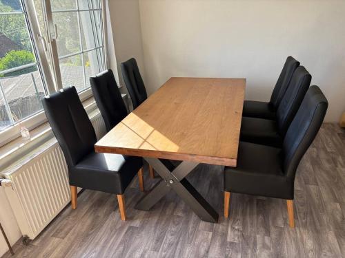 a wooden table with four black chairs around it at Wooden Bridge Residence in Karlovy Vary