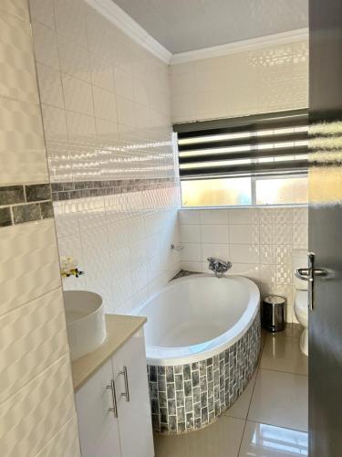 a white bathroom with a tub and a sink at Elyon Suites in Kempton Park