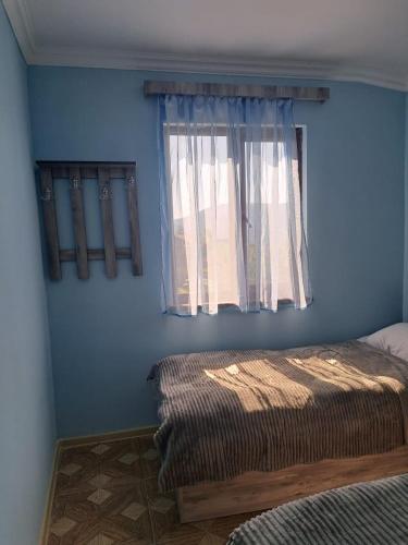 - une chambre avec un mur bleu et une fenêtre dans l'établissement Elmira B&B, à Tatev