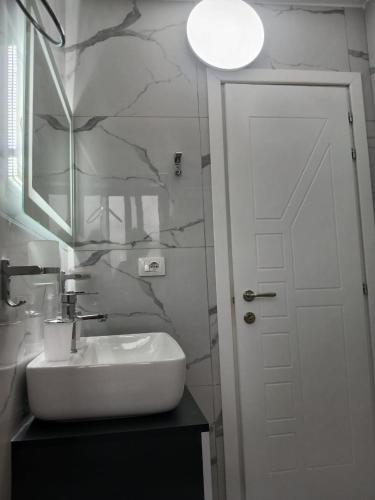 a white bathroom with a sink and a mirror at Apartament Cela in Çorovodë