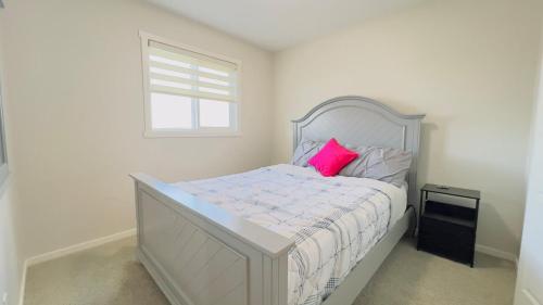a white bedroom with a pink pillow on a bed at Calgary Airport Getaway Spacious 3BR Full Home in Calgary