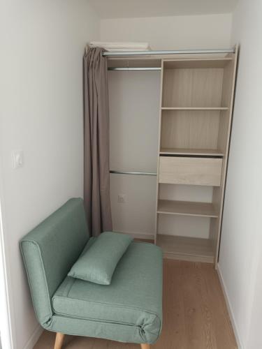 a green chair in front of a closet at Studio cabine avec terrasse in Fort-Mahon-Plage