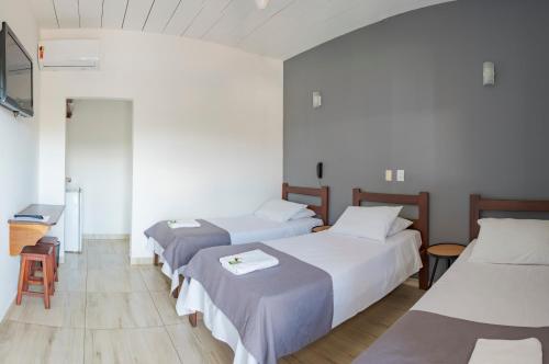 a room with three beds and a table at Pousada Dona Emilia in Brotas