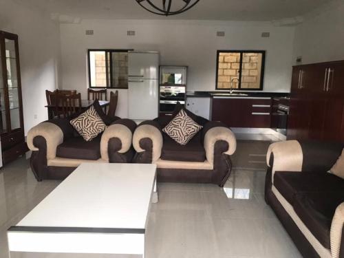 a living room with two couches and a table at 1 bed apartment with pool & gym in Mpemba