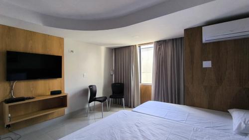 a hotel room with a bed and a flat screen tv at Apartamento a beira mar in Natal
