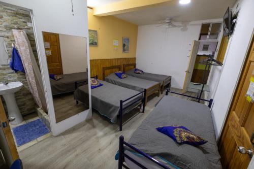 a room with three beds and a mirror at Hostal Pampaloja Antof in Antofagasta
