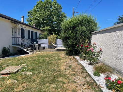 ein Hinterhof eines Hauses mit einer Bank und Blumen in der Unterkunft Nid douillet a la campagne in Saint-Jean-de-Bournay