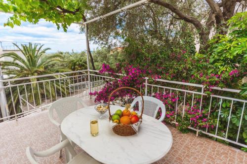 a table with a basket of fruit on a balcony at Apartmani Steni in Sveti Stefan