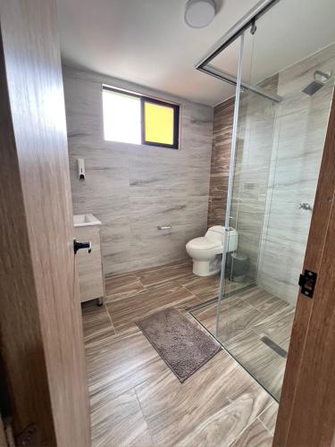 a bathroom with a toilet and a glass shower at Meraki Urban Lofts in Quibdó