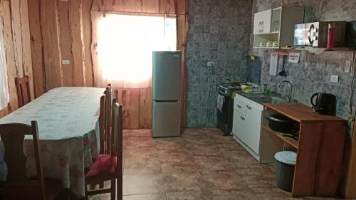 a kitchen with a refrigerator and a table in it at Cabaña Cunco parcela in Cunco