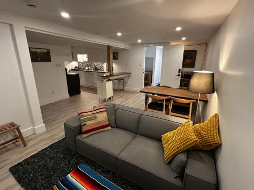 een woonkamer met een grijze bank en een keuken bij The Orange Door Bungalow- 2-BR w private yard, walkable to cafes & restaurants, 10 min to DT in Vancouver