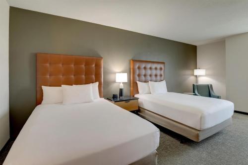 a hotel room with two beds and a chair at Drury Inn & Suites Dayton North in Dayton