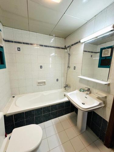 un bagno con vasca, WC e lavandino di Karimz Backpackers a Abu Dhabi