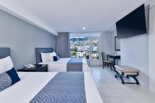a hotel room with two beds and a balcony at Krystal Beach Acapulco in Acapulco
