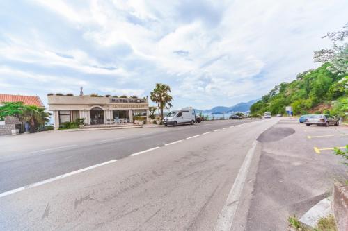 an empty street with cars parked on the side of the road at Apartmani Steni in Sveti Stefan