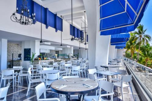 a restaurant with blue tables and white chairs at Krystal Beach Acapulco in Acapulco