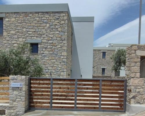 un edificio con una valla de madera y una pared de piedra en Alba Lilia II, en Pitsidia