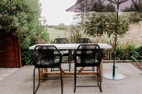 a white table with four chairs and an umbrella at Te Mata Views Resort in Havelock North